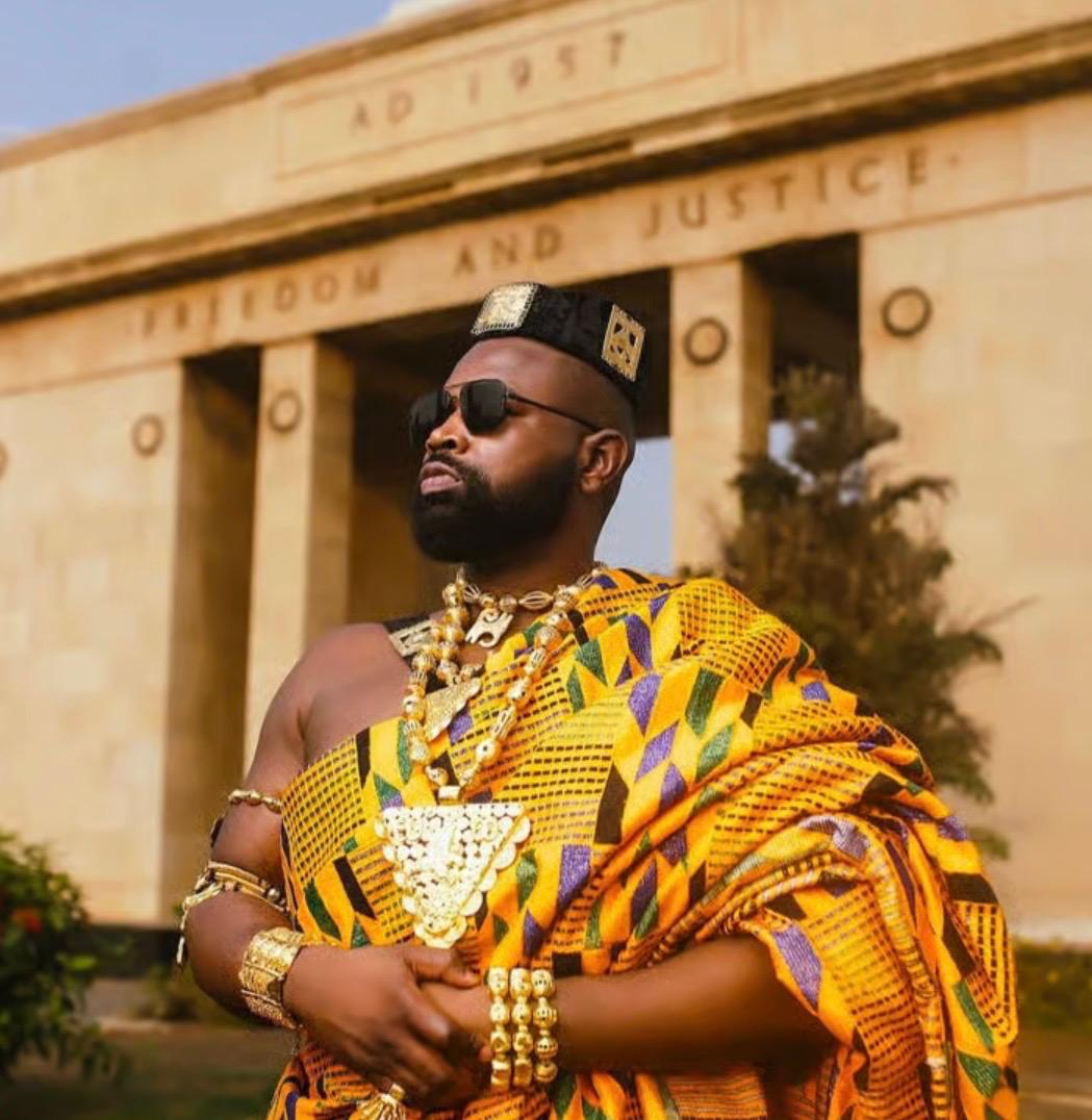 A man in royal kente attire before the Independence Arch in Accra