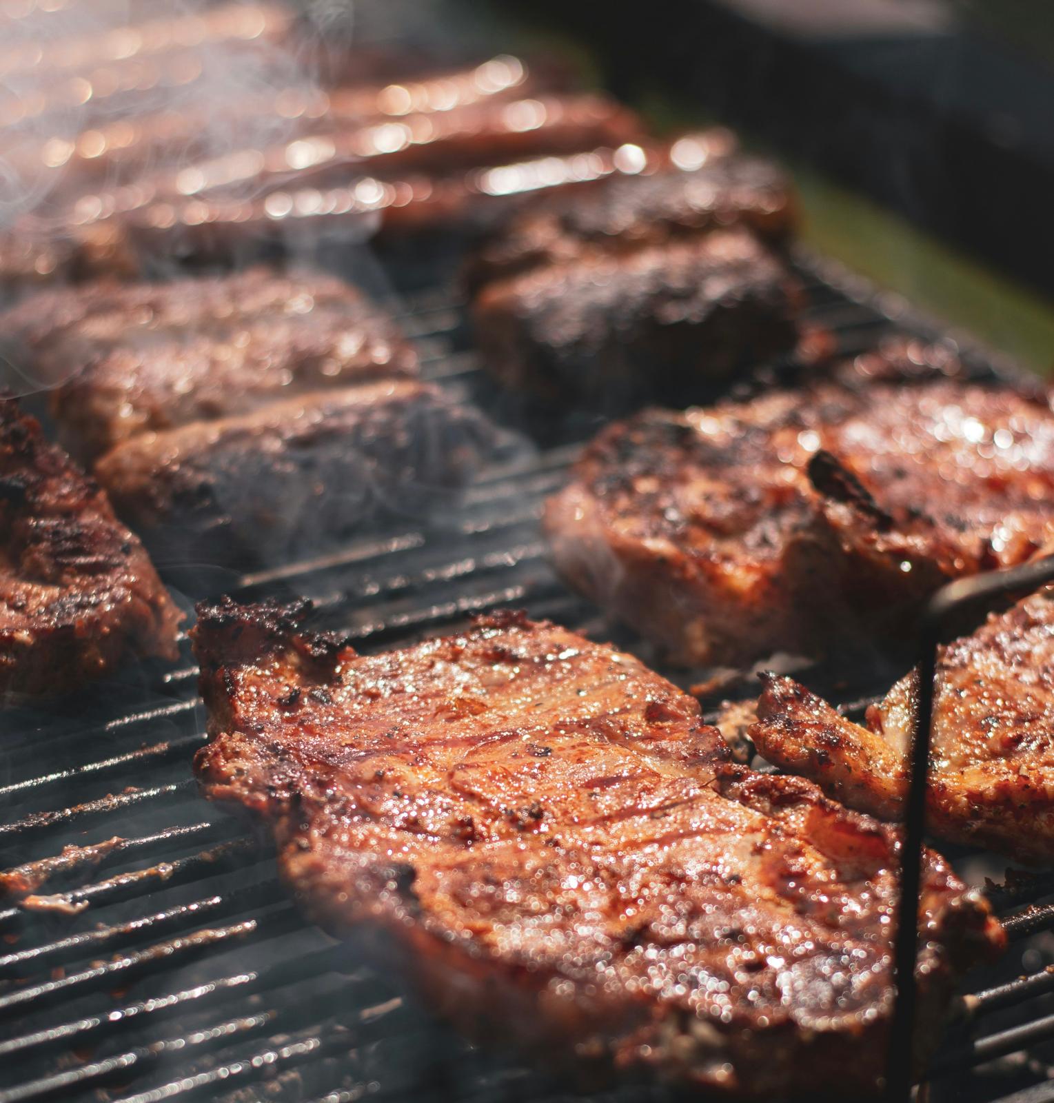 Steaks and sausages grilling over an open barbecue