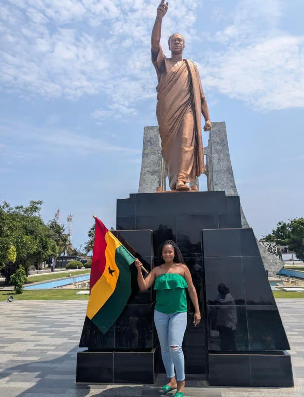 A visitor holding the Ghana flag beneath Dr Kwame Nkrumah’s statue at Memorial Park