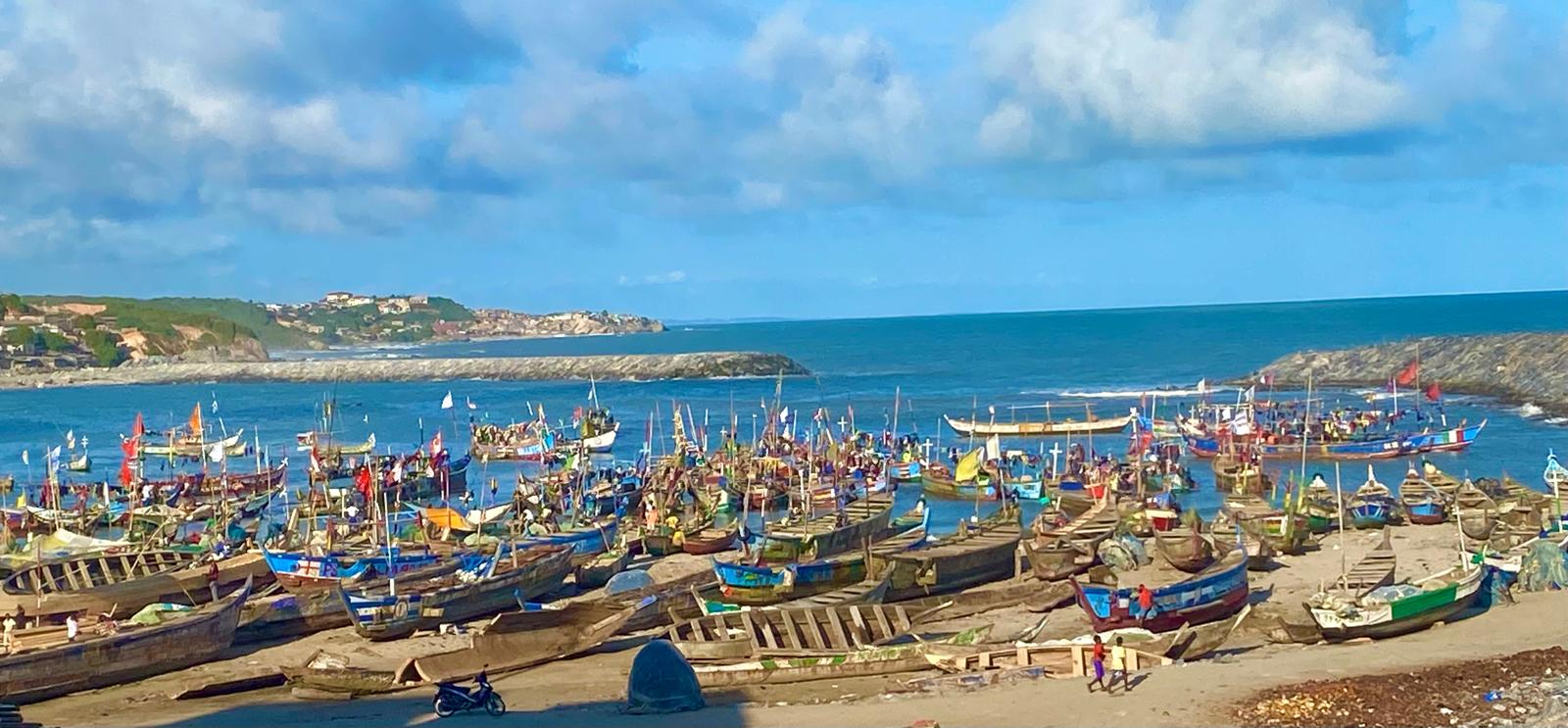 Colourfully painted fishing canoes crowded along Elmina Bay