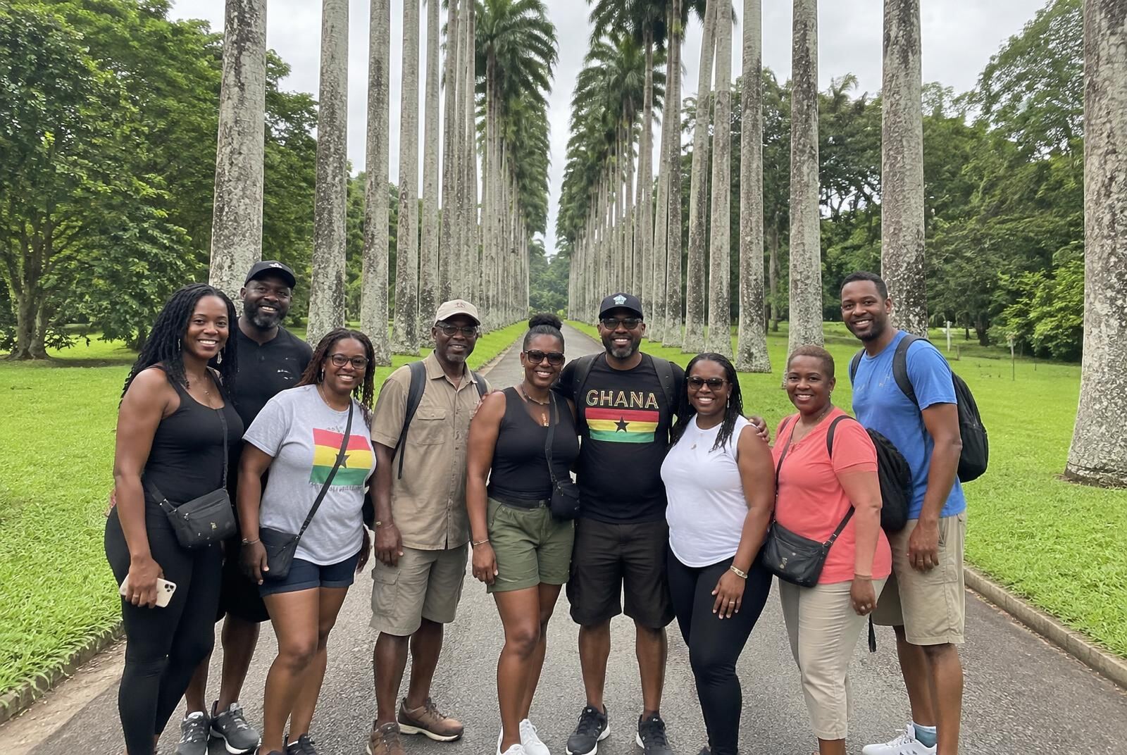 A group of travellers posing on the royal palm avenue at Aburi Botanical Gardens